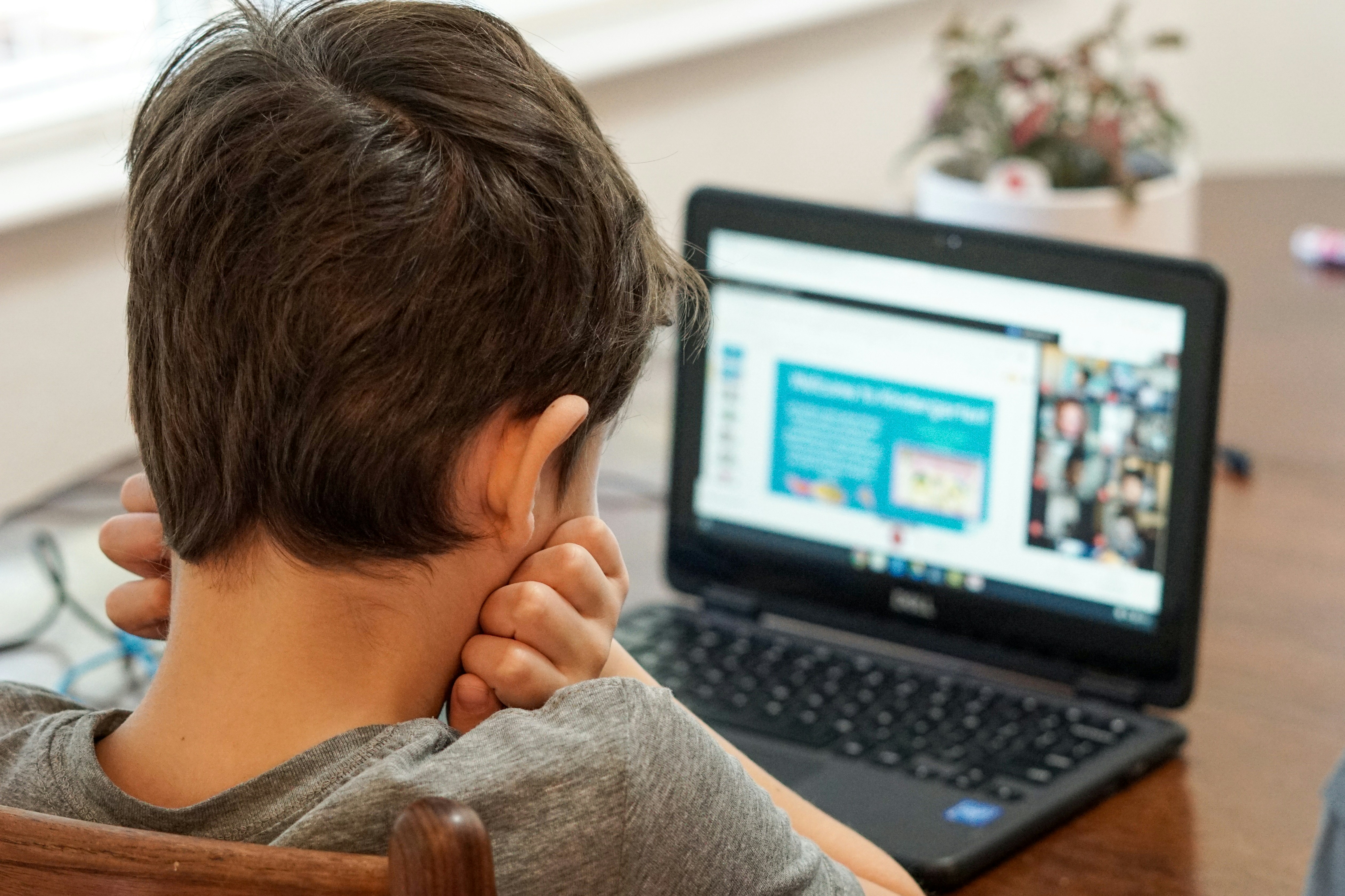 Image shows a child sitting at a desk with a laptop